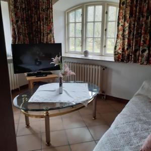 a living room with a glass table and a tv at Hackerhof-Suedwohnung in Morsum