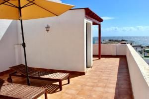 een balkon met een bank en een parasol bij 3BDR Casa El Poris in Poris de Abona