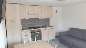 a small kitchen with wooden cabinets and a couch at Le 4 Stagioni in Comacchio