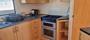 a small kitchen with a stove and a sink at Lovely Caravan at Ingoldmells just behind sealands in Ingoldmells