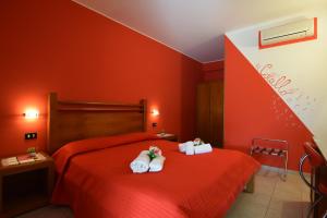 - une chambre rouge avec 2 lits et des serviettes dans l'établissement Hotel Iride by Marino Tourist, à San Vito Lo Capo