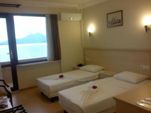 ein Hotelzimmer mit zwei Betten und einem Fenster in der Unterkunft Kaunos Hotel in Koycegiz
