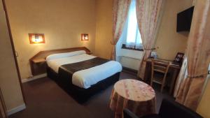 シェルブール・アン・コタンタンにあるHotel Angleterreのベッドとテーブルが備わるホテルルームです。