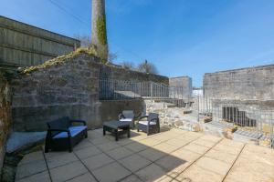 two chairs and a table on a patio next to a wall at Furness in St Austell