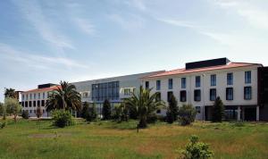 un gran edificio blanco con palmeras en un campo en INATEL Cerveira Hotel en Vila Nova de Cerveira