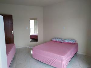 a pink bed in a white room with a mirror at RECANTO BUSCAPE in Alto Caparao