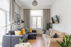 a living room with a blue couch and yellow pillows at Lion Apartments - London in Sopot