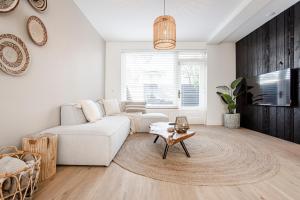 Una sala de estar con un sofá blanco y una mesa. en Marley’s Beachhouse - Luxury Apartment with garden, en Zandvoort