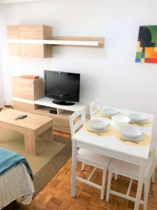 - un salon avec une table, des chaises et une télévision dans l'établissement Tranquilidad al lado del Centro Parking incluido, à Oviedo