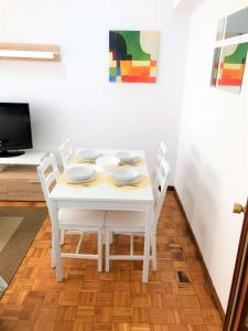 una mesa de comedor blanca con cuatro platos. en Tranquilidad al lado del Centro Parking incluido en Oviedo