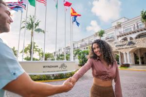 a man and a woman shaking hands in front of a building at Wyndham Alltra Playa del Carmen Adults Only All Inclusive in Playa del Carmen