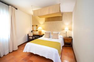 a bedroom with a bed with a yellow and white blanket at Hospederia de Santo Domingo in Pedraza-Segovia