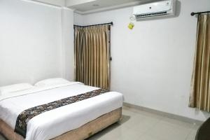 a bedroom with a bed and a window with curtains at Tiray Homestay Syariah Yogyakarta Mitra RedDoorz in Salakan