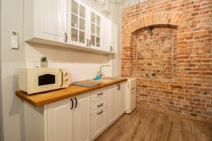 a kitchen with white cabinets and a brick wall at Apartament Starówka 10 (Miodova) in Toruń