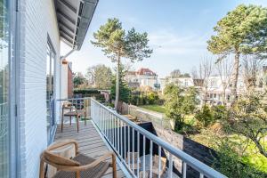 Elle comprend un balcon avec 2 chaises et des arbres. dans l'établissement Marley’s Beachhouse - Luxury Guest Room with balcony, à Zandvoort