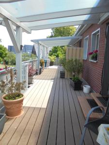 a deck with a white pergola and potted plants at Apartement Meerblick in Wunstorf