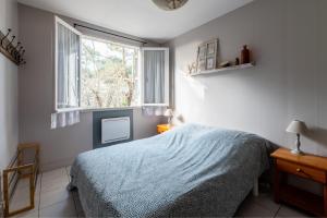 a bedroom with a bed and a window at LA PETITE MAISON DU LAC in Biscarrosse