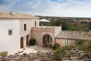 una vista exterior de una casa de piedra con patio en Tenuta Cammarana en Donnafugata