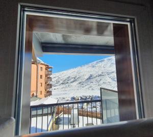 uma vista para uma montanha de neve a partir de uma janela em Terraza espectacular sol y vistas em Pas de la Casa