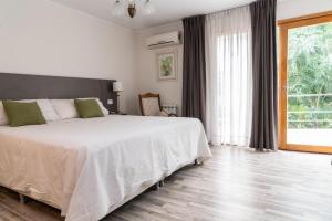 a bedroom with a white bed and a large window at La Morada Petit Hotel in Neuquén