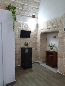 a living room with a stone wall and a tv at Lungomare Modugno in Polignano a Mare