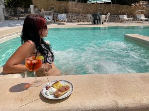a woman sitting at a table with a plate of food next to a pool at Casale degli Angeli Ostuni in Cisternino
