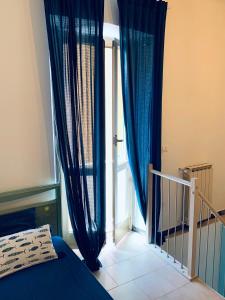 a bedroom with blue curtains and a large window at Appartamento SoloSoleMare in Portovenere
