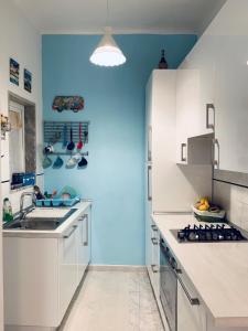 une cuisine avec des placards blancs et un mur bleu dans l'établissement Appartamento SoloSoleMare, à Portovenere