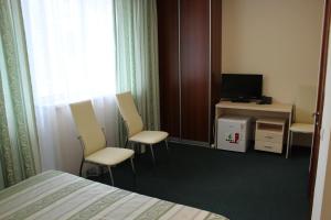 a hotel room with a bed and chairs and a television at Bely Dom Hotel in Krasnoyarsk