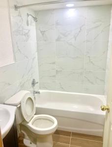 a bathroom with a white tub and a toilet and a sink at Bestway Motel in Windsor