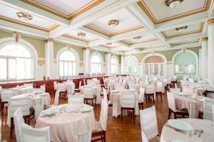 un salón de banquetes con mesas y sillas blancas en Palace Hotel - Poços de Caldas, en Poços de Caldas