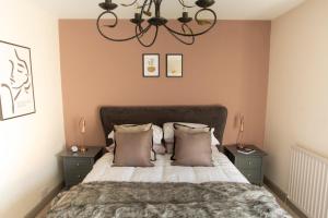 1 dormitorio con cama con almohadas y lámpara de araña en Beautiful Luxe Victorian Townhouse - 5 mins walk from Warwick Castle & town, en Warwick