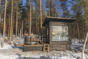 eine kleine Hütte im Wald im Schnee in der Unterkunft Northern Lights Glass Igloo Getaway For Couples in Rovaniemi
