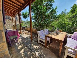 eine Terrasse mit einem Holztisch und Stühlen in der Unterkunft Mor Panjurlu Bohem Tasarım Ev - Kazdağları & Deniz in Ayvacık
