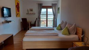 2 Betten in einem Zimmer mit einem TV und einem Fenster in der Unterkunft Gästehaus - Camping- Weinhof Radl in Klöch