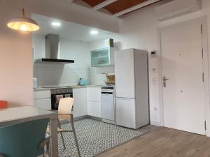 a kitchen with white appliances and a table and chairs at Can Llavi in Canet de Mar