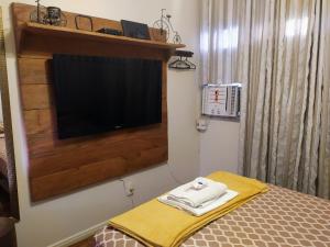 a bedroom with a bed and a flat screen tv at ACONCHEGANTE QUARTO - PRAIA do CANTO in Vitória