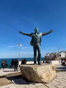 a statue of a man with his arms out at Lungomare Modugno in Polignano a Mare