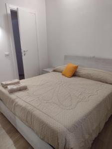 una camera bianca con un grande letto con un cuscino arancione di La Castellana a Spina