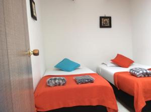Dos camas en una habitación con naranja y azul en The Palma Home, en Bogotá