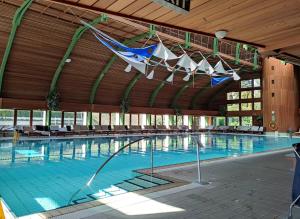a large swimming pool with a large wooden building at Spa Residence Carbona Siesta Apartman in Hévíz