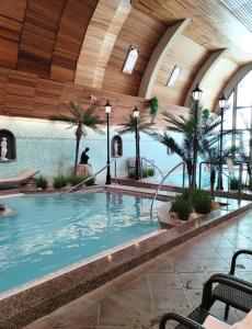 a large indoor pool with palm trees in a building at Spa Residence Carbona Siesta Apartman in Hévíz