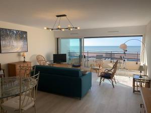- un salon avec un canapé bleu et une vue sur l'océan dans l'établissement Appt traversant vu Mer et Dunes avec Garage, à Le Touquet-Paris-Plage