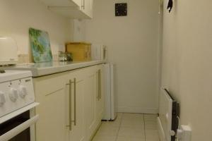 a kitchen with white cabinets and a stove top oven at Ty Hen - Quirky Grade II Listed Cottage in Blaenau-Ffestiniog
