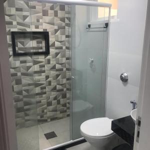 La salle de bains est pourvue de toilettes et d'une douche en verre. dans l'établissement Apartamento com vista para o mar, à Arraial do Cabo
