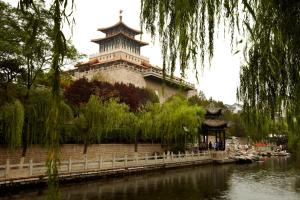 a building with a tower next to a river at Melia Jinan in Jinan
