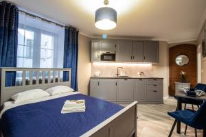 1 dormitorio con 1 cama azul y cocina en Nicolaus Apartment, en Toruń
