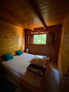 a bed in a wooden cabin with a window at Maison 2 chambres proche Dijon chalet niché dans la nature in Saint-Maurice-sur-Vingeanne
