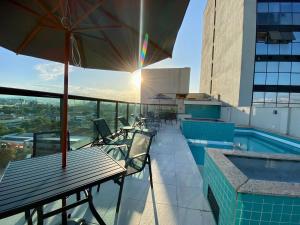 a balcony with a table and umbrella on a building at Logic Hotel Volta Redonda in Volta Redonda