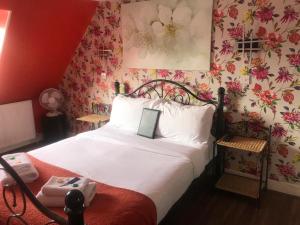 1 dormitorio con cama blanca y papel pintado con motivos florales en Kempfield House, en Brighton & Hove
